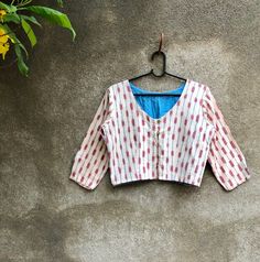 "Creme and Red Ikat cotton blouse is perfect to wear with any saree, dress as open crop jacket or as a crop top. It comes with 3/4th sleeves and 'v' neck at front.  Comes with button and loop fastenings at front.  Has blue lining inside.  It is a very versatile top and can be worn in many ways. Measurements: Chest: 37\" Waist: 32\" Length: 16\" It is 100% cotton  I would recommend gentle hand washing separately. Colour may run in the first few washes. Thank you for looking and supporting handmad Festive White Cotton Tops, Fitted Cotton Choli With Kalamkari Print, Cropped Cotton Padded Blouse, Festive Cotton Blouse With Block Print, Cotton Long Sleeve Choli For Festivals, Festive Cotton Handloom Tops, Festive Handloom Cotton Tops, Fitted Cotton Blouse For Navratri, Cotton Padded Blouse Piece For Navratri