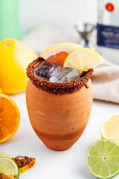 a drink with lemons and limes around it on a white countertop next to other citrus fruits