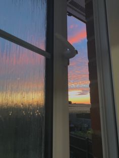 the sun is setting behind an open window