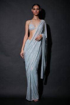 Silver pre draped saree in net base with all-over embellishments with crystal beads on the edges. Comes with bralette style blouse.
Components: 2
Pattern: Embellished
Neckline: Plunged V-Neck
Sleeve Type: Sleeveless
Fabric: Net
Color: Silver
Other Details: 
Pre-draped saree
Backless blouse
Crystal beads on edges
Occasion: Cocktail - Aza Fashions Luxury Silver Lehenga For Festivals, Luxury Designer Silver Blouse Piece, Luxury Cutdana Saree For Eid, Luxury Silver Saree For Festive Occasions, Luxury Chanderi Party Wear Pre-draped Saree, Luxury Silver Designer Wear Blouse Piece, Luxury Silver Traditional Wear, Luxury Saree Skirt For Party Wear, Luxury Silver Saree For Party