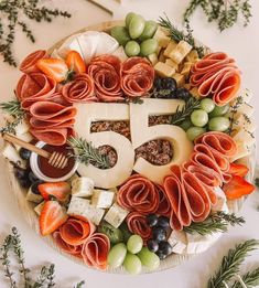 a platter filled with cheese, meats and vegetables on top of a table