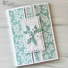 a close up of a card with flowers on the front and bottom, in white and green