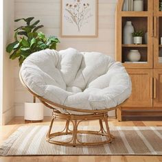 a white chair sitting in front of a book shelf next to a potted plant