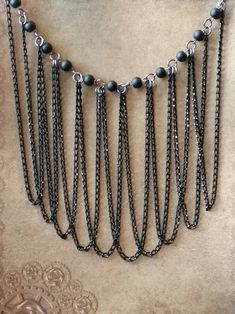 This draped bib chain necklace in gunmetal and black is one of my newest projects. It features matte black glass beads and multiple lengths of draped chain. The necklace has 11 8mm matte black beads wired onto eye pins and connected with gunmetal-toned jump rings. Attached to the jump rings are ten 9 inch lengths of black chain. The chains are draped and they hang down beautifully. I finished the necklace with a black chain and a lobster claw clasp for easy use. The necklace is 20 inches long no Black Bohemian Metal Chain Necklace, Black Metal Bohemian Chain Necklace, Bohemian Black Metal Chain Necklace, Black Metal Jewelry With Ball Chain, Black Bohemian Chain Necklace With Adjustable Chain, Bohemian Black Chain Necklace With Adjustable Chain, Bohemian Black Adjustable Chain Necklace, Black Metal Dangle Chain Necklace, Necklace Chain Lengths