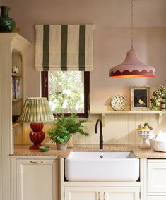 a kitchen with a sink, window and hanging lamp in the corner next to it