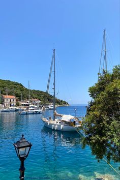 Photograph of a Boat viewed from above on very blue sea, in a small Greek harbour, with a few houses visible on the opposite shore line. Kefalonia Aesthetic, Kefalonia Greece Aesthetic, Greece Aesthetics Beach, Athens Greece Aesthetic, Athens Beach, Kefalonia Greece, Athens Travel