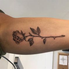 a black and white rose tattoo on the right arm, with two leaves coming out of it