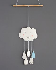 a cloud and raindrops hanging from a wooden hanger on a gray wall