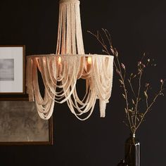 a white chandelier hanging from a ceiling next to a vase with flowers in it