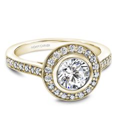 a yellow gold engagement ring with diamonds on the band and a center stone surrounded by small round