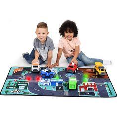 two young children playing with toys on a play mat in front of a white background