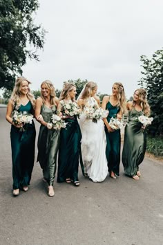 a group of women standing next to each other holding bouquets in their hands and wearing green dresses