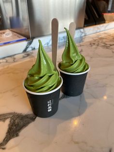 two cupcakes with green frosting on top sitting on a counter in a restaurant