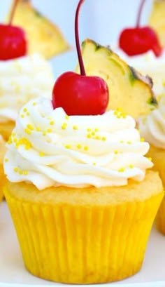 cupcakes with white frosting and cherries on top, topped with pineapple slices