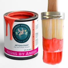 an orange paint can next to a red and white brush that has been dipped with acrylic