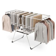 an ironing board with clothes hanging on it and two racks holding sweaters, shirts and jackets