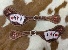 two leather collars with playing cards on them sitting on top of a cowhide