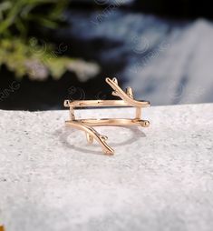 a gold ring with two branches on it sitting on top of a white stone surface