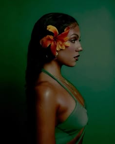 a woman with flowers in her hair is posing for a photo against a green background