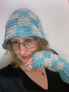 This stylish crochet set features a cozy bucket hat and matching fingerless gloves, handmade with soft alpaca wool. The checkered pattern in soothing teal and neutral gray offers a unique touch, perfect for cool weather wear. The hat's wide brim adds both charm and sun protection, while the gloves keep hands warm while allowing for easy movement. Ideal for gifting or adding a cozy-chic accessory to your winter wardrobe. Wool Crochet, Stylish Crochet, Crochet Bucket, Crochet Bucket Hat, Crochet Set, Weather Wear, Cozy Chic, Bucket Hats, Chic Accessories