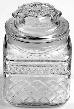 a clear glass jar with a lid and diamond design on the front, sitting on a white surface