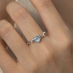 a woman's hand with a ring on it and a blue stone in the middle