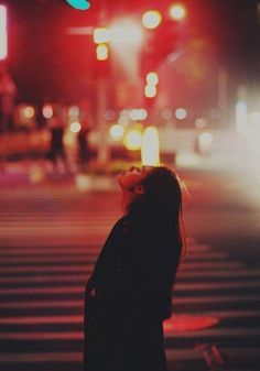 a woman standing in the middle of a cross walk at night with her eyes closed