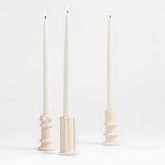 three white candles sitting next to each other in front of a white background with no one around them