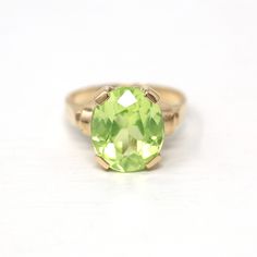 "Beautiful vintage circa 1940s era 10k yellow gold created green spinel ring! This lovely statement ring features an eye catching bright green 5.84 carat oval faceted created spinel, that is securely prong set. There are classic designs on the shoulders, and the shank is free of design. A wonderful 1940s era ring, featuring a pretty green stone!  ERA - Circa 1940s - Retro METAL / MATERIAL - 10k yellow gold, created spinel (approx. 5.84 CT) (Created spinel contains essentially the same chemical c Classic Green Emerald Ring For Collectors, Vintage Oval Emerald Ring In 14k Gold, Heirloom Oval Green Ring, Classic Oval Green Rings, Vintage 14k Gold Emerald Ring With Center Stone, Classic Green Birthstone Ring In 14k Gold, Vintage Yellow Gold Emerald Ring With Center Stone, Vintage Green Solitaire Ring, Classic Green Oval Ring