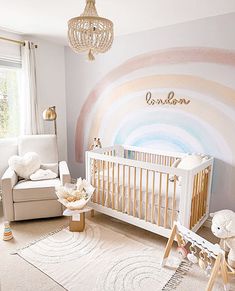 a baby's room decorated in pastel colors with a rainbow painted on the wall