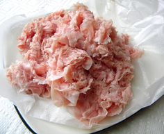 raw meat on a white plate sitting on top of a cloth covered tablecloth, ready to be cooked