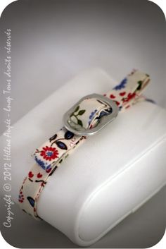 a white case with a flowered design on it and a silver buckle around the clasp