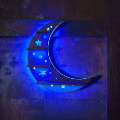 the moon is lit up with stars on it's side, against a wooden background