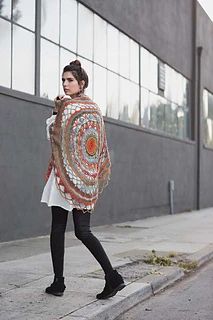 a woman is walking down the street wearing a colorful shawl and black booties