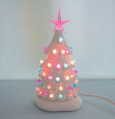 a small plastic christmas tree with lights on it's base and a pink star