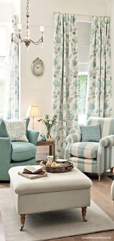 a living room filled with furniture and a chandelier hanging from the ceiling over a window