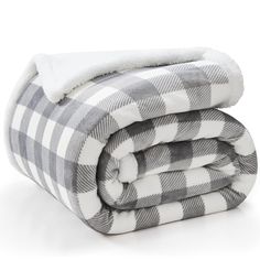 the grey and white checkered blanket is folded up on top of each other,