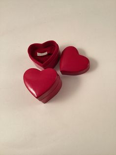 three red heart shaped boxes sitting next to each other on a white surface with a diamond in the middle