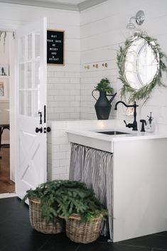 a kitchen with white walls and black tile flooring, christmas wreaths on the wall