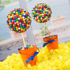 two buckets filled with candy sitting on top of yellow plastic bags and covered in gummy balls