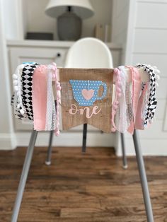 a chair decorated with pink, blue and white ribbon on the legs that says one