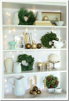 a white shelf filled with christmas decorations and greenery on top of it's shelves