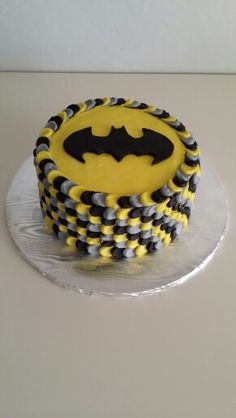 a batman cake with yellow and black icing on a silver platter, ready to be eaten