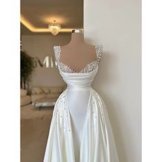 a white wedding dress on display in front of a wall with a mirror behind it