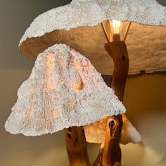 a lamp that is sitting on top of a wooden stand with two mushrooms under it