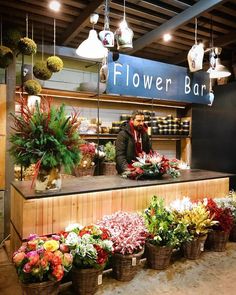 a flower shop with flowers in baskets on the counter and people standing at the counter