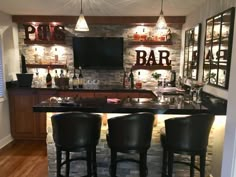 a bar with three stools in front of it and bottles on the back wall