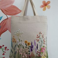 a bag with flowers painted on it hanging from a wall next to a flower painting