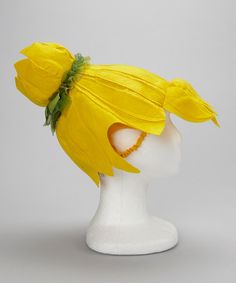 a white mannequin head with a yellow flower on it