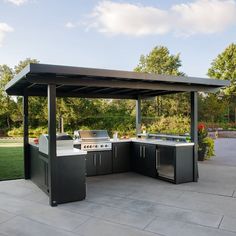 an outdoor kitchen with grills and sink in the middle of a patio area next to trees